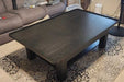 The Game Theory Tables The Origins Coffee Table in a living room setting, displaying a smooth, dark tabletop