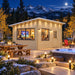 The Eze Breeze Sunroom Cabin Freedom Office illuminated on a clear Colorado night, with adults watching sports through the expansive windows beside a steaming hot tub and snowy Rocky Mountain peaks.
