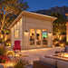 The Versa 107 70MM Freedom Office glowing during a bright Nevada night as friends watch a sports game inside, surrounded by illuminated desert landscaping and distant mountains.
