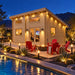 The Versa 240 70MM Freedom Office illuminated at night in a Nevada backyard, with friends watching sports inside beside a pool, fire pit, and desert garden.
