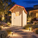 The Wee Wee House 33 outdoor bathroom illuminated at night in a landscaped Nevada residential backyard with desert plants, stepping stones, and pathway lights.