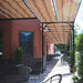 The long sidewalk patio of a restaurant is lined with tables beneath a colorful striped Structureworks Silhouette Aluminum Patio Cover & Pergola