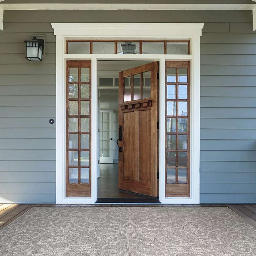 The rug styled at a front porch shows how Couristan Monaco Indoor/Outdoor Rug - Summer Quay/Cocoa Natural enhances entryway charm