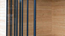 The tall, vertical glass panels of the GardenHouse24 USA ALU Concept 44Q Garden Room are neatly aligned in a wooden wall