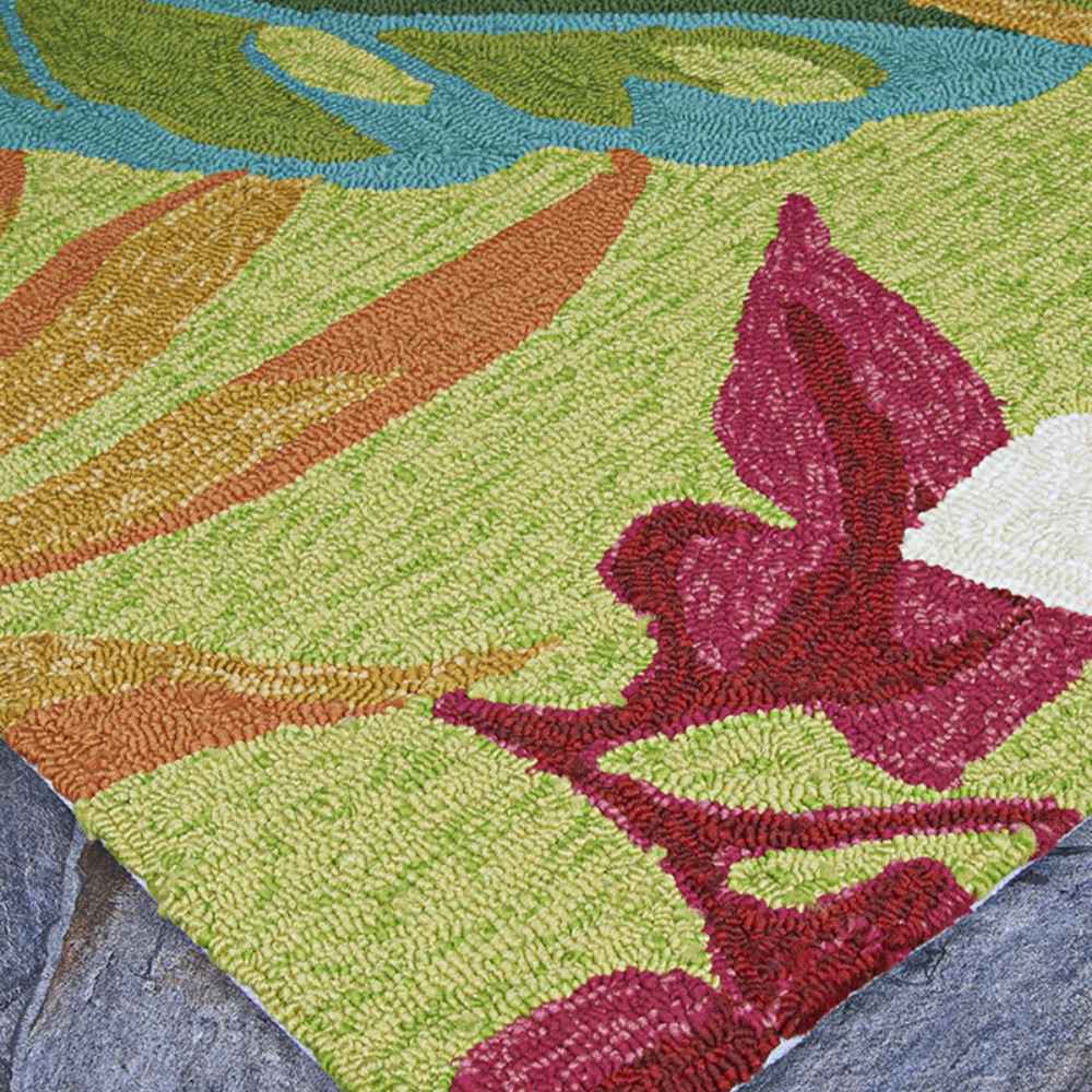 The corner of the Couristan Covington Indoor/Outdoor Rug - Painted Fern/Fern-Red rests on stone flooring