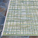 The edge of the Couristan Cape Indoor/Outdoor Rug - Falmouth/Ivory-Hunter is displayed on stone flooring, revealing clean stitching and its striped design