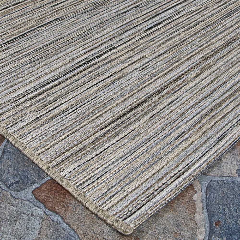 The edge of the Couristan Cape Indoor/Outdoor Rug - Hinsdale/Light Brown-Silver is neatly finished and rests on a stone surface