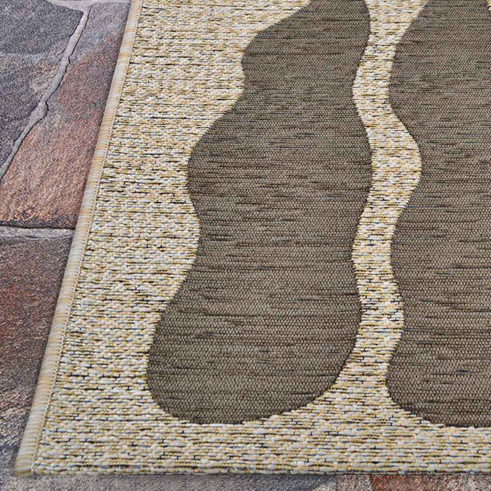 The edge of the Couristan Castille Indoor/Outdoor Rug - Fiore/Mocha rests neatly on a stone surface