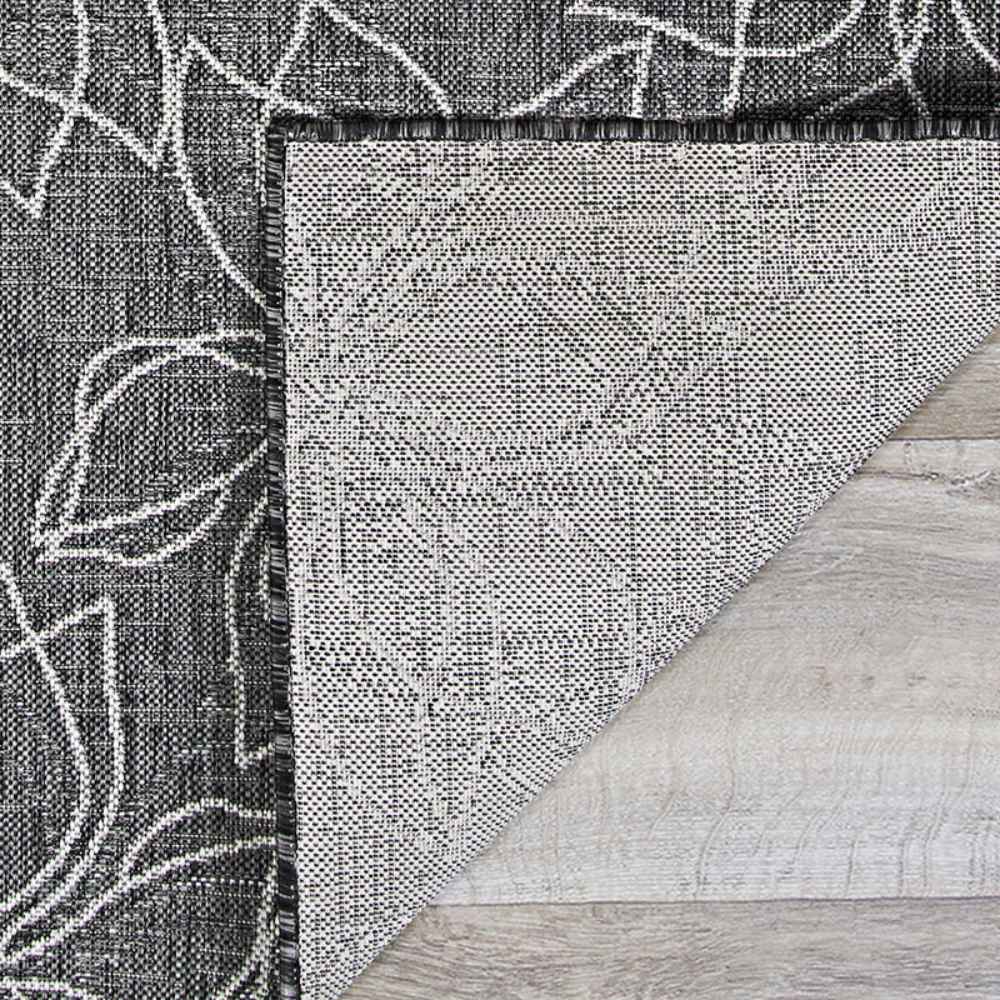 The flipped corner of the Couristan Charm Indoor/Outdoor Rug - Botanical/Ash displays the backside and its clean, well-structured weave