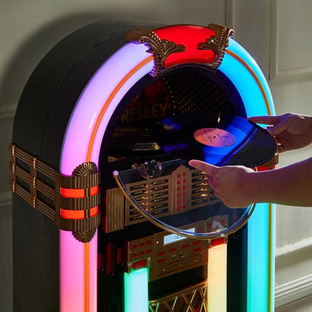 The image displays a person loading a vinyl record into Arkrocket x Elvis Presley Saturn V Full Size Bluetooth Vinyl Record Jukebox