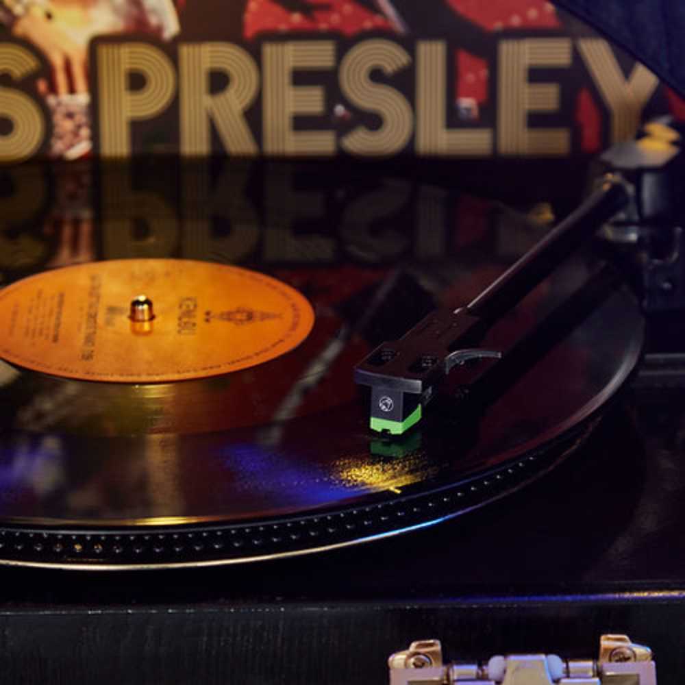 The image is a close-up of a spinning vinyl record being played on the Arkrocket x Elvis Presley Saturn V Full Size Bluetooth Vinyl Record Jukebox