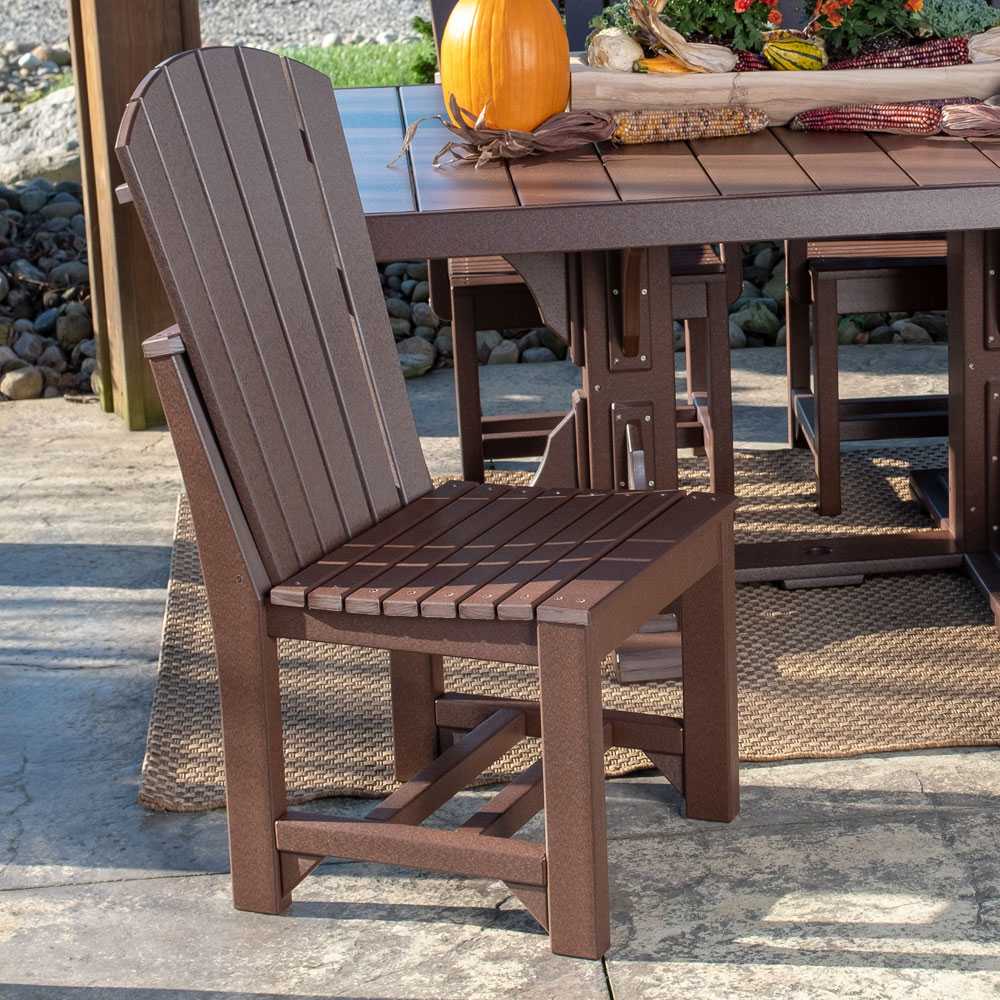 The image shows an antique mahogany LuxCraft Adirondack Side Chair placed next to a matching outdoor table with autumn decorations, on a stone patio