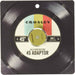 The image shows the Crosley 45'er Aluminum Adaptor - Green, designed to resemble a vinyl record sleeve with a colorful label in the center