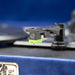 The image shows the needle head of the Arkrocket Curiosity Suitcase Bluetooth Turntable (Klein Blue) with a green stylus at the end of the tonearm