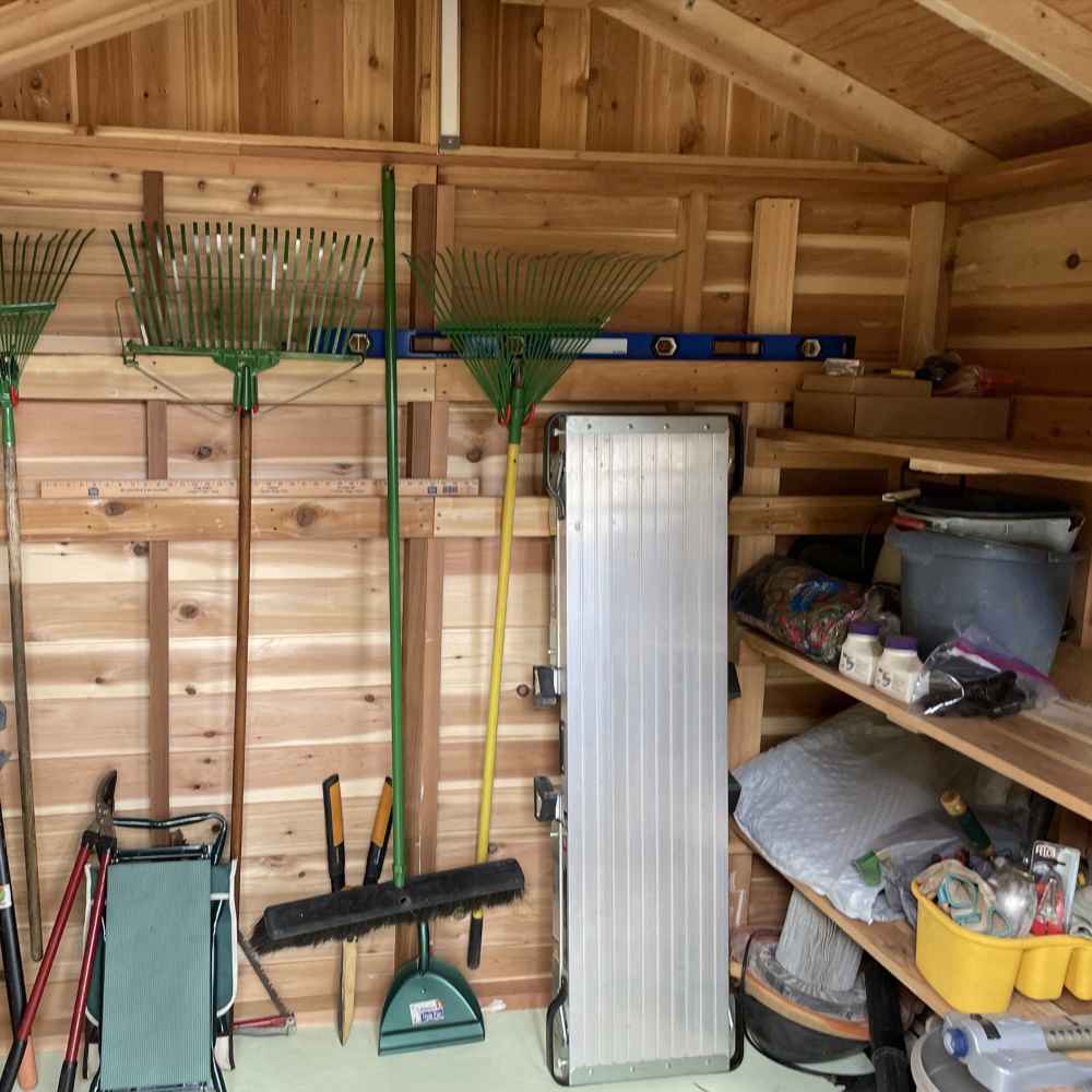 The inside of a wooden shed with shelves, garden tools, and storage bins organized along the walls of the Outdoor Living Today 8×8 Gardener Shed