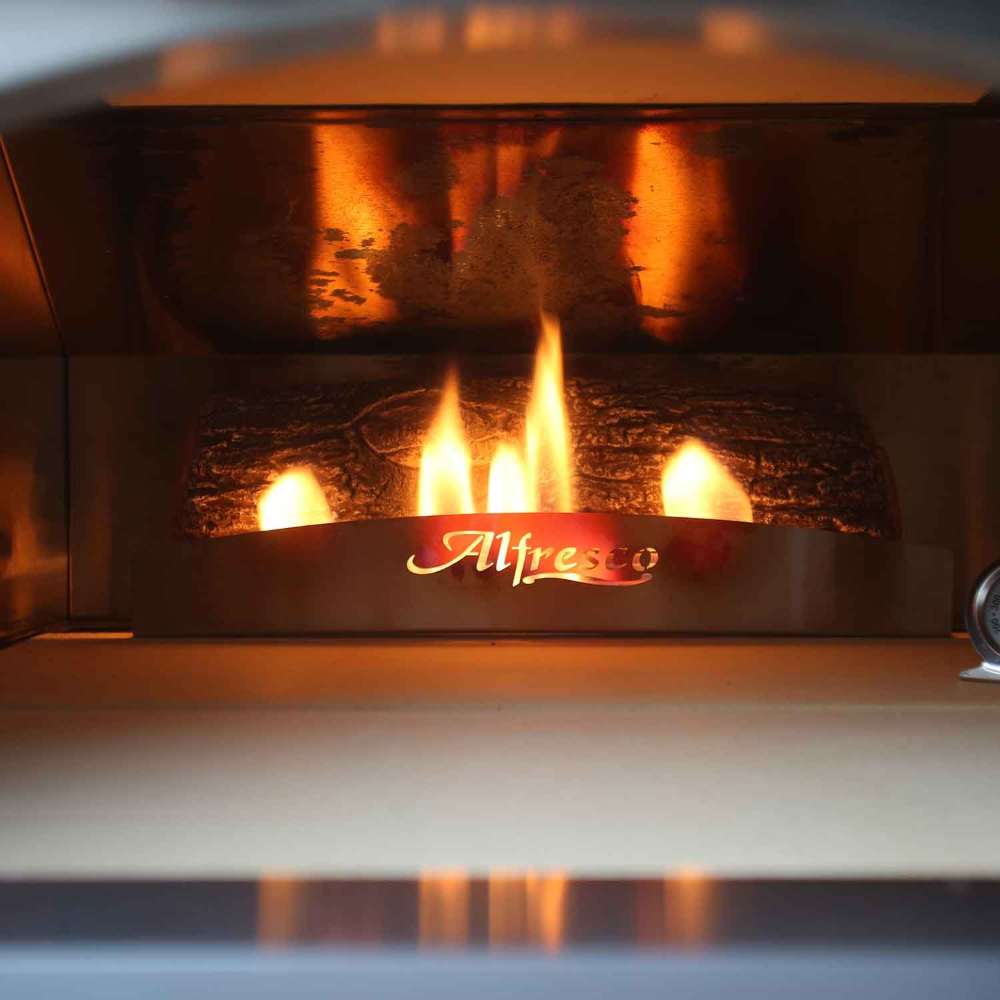 The inside of the Alfresco Grills 30 Pizza Oven Plus - Built-In glows with an open flame