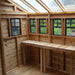The interior of the Outdoor Living Today 8×8 Sunshed Garden Shed features natural wood walls, multiple windows, and a built-in workbench under a clear sloped roof