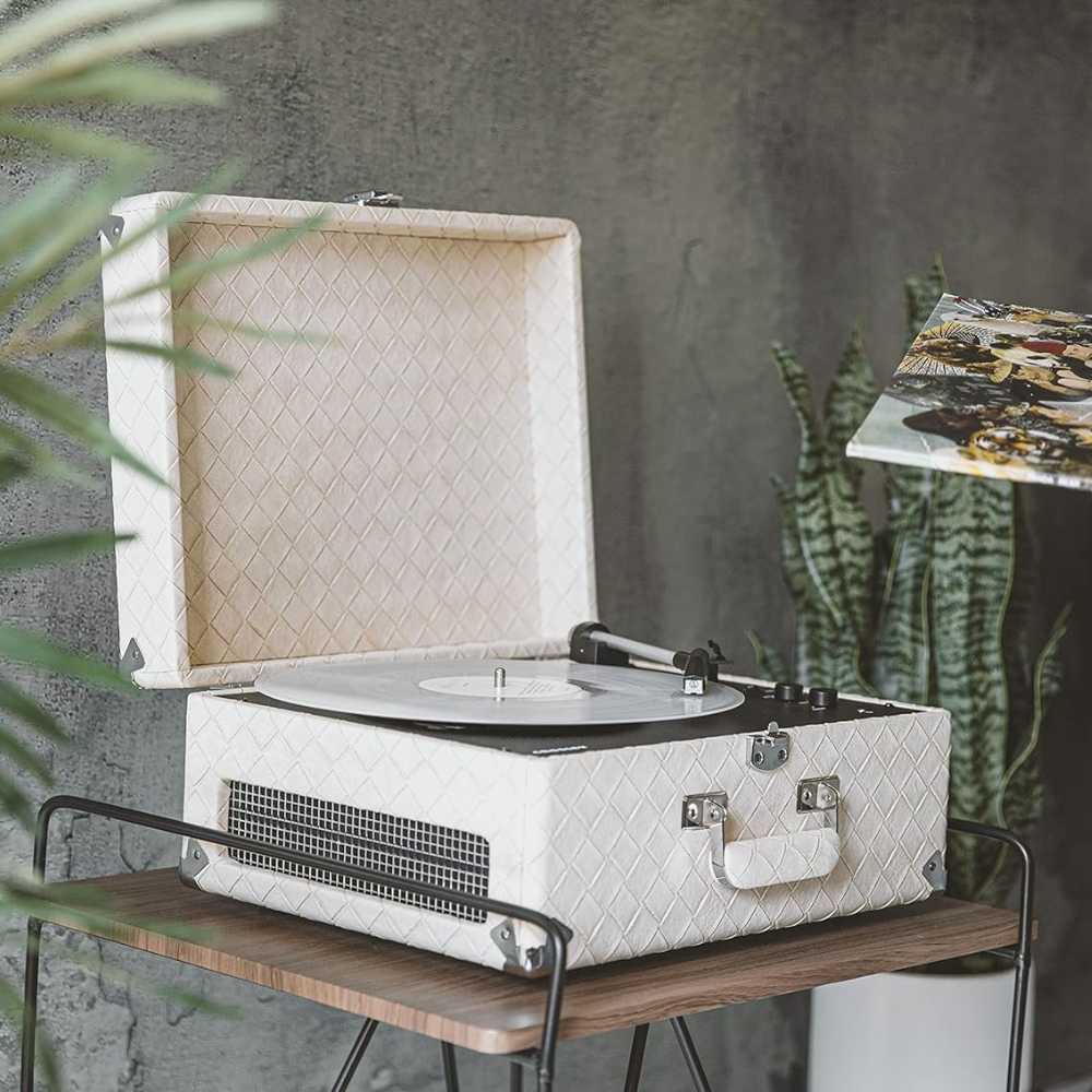 The open Crosley Anthology Portable Turntable - Light Tan is displayed on a small wooden stand, with a vinyl record spinning inside a textured light tan case