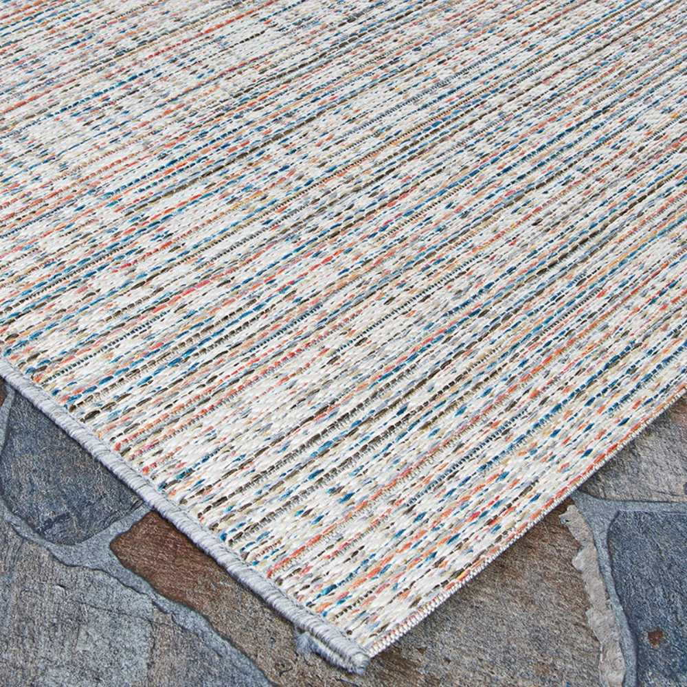 The textured surface of the Couristan Cape Indoor/Outdoor Rug - Falmouth/Ivory-Coral laid over a stone floor