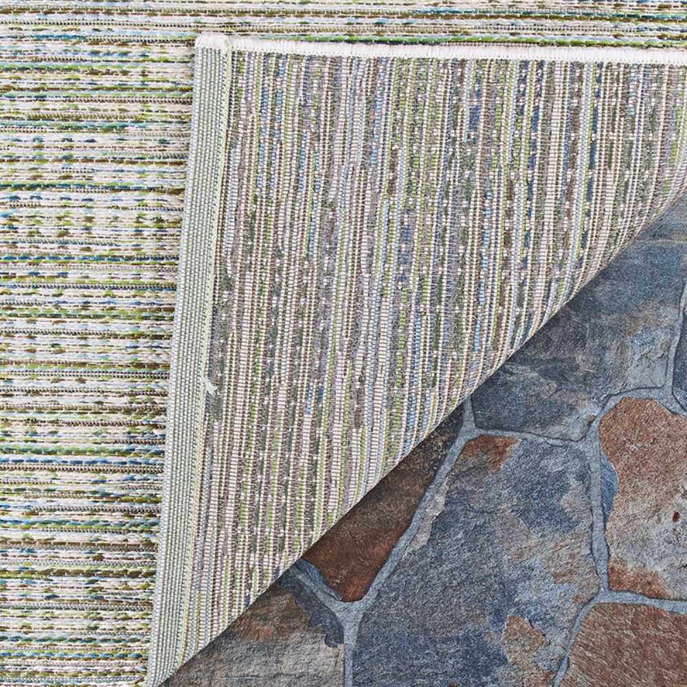 The underside of the Couristan Cape Indoor/Outdoor Rug - Falmouth/Ivory-Hunter is flipped over to show its backing and stitched edges on a stone floor