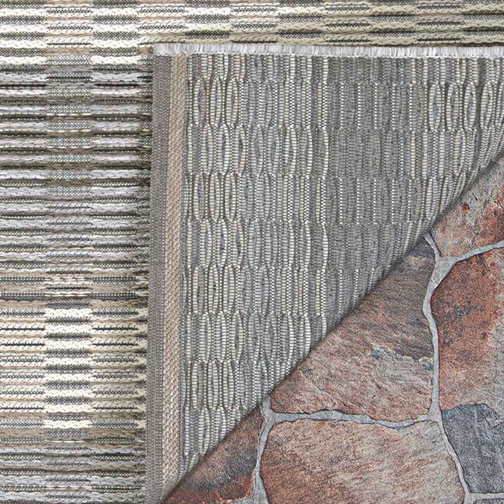 The underside of the Couristan Cape Indoor/Outdoor Rug - Torrent/Sky Blue-Grey is shown flipped up, revealing its backing and quality stitching