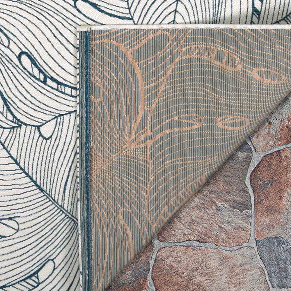 The underside of the Couristan Castille Indoor/Outdoor Rug - Palma/Petrol is shown folded over to reveal a complementary woven backing