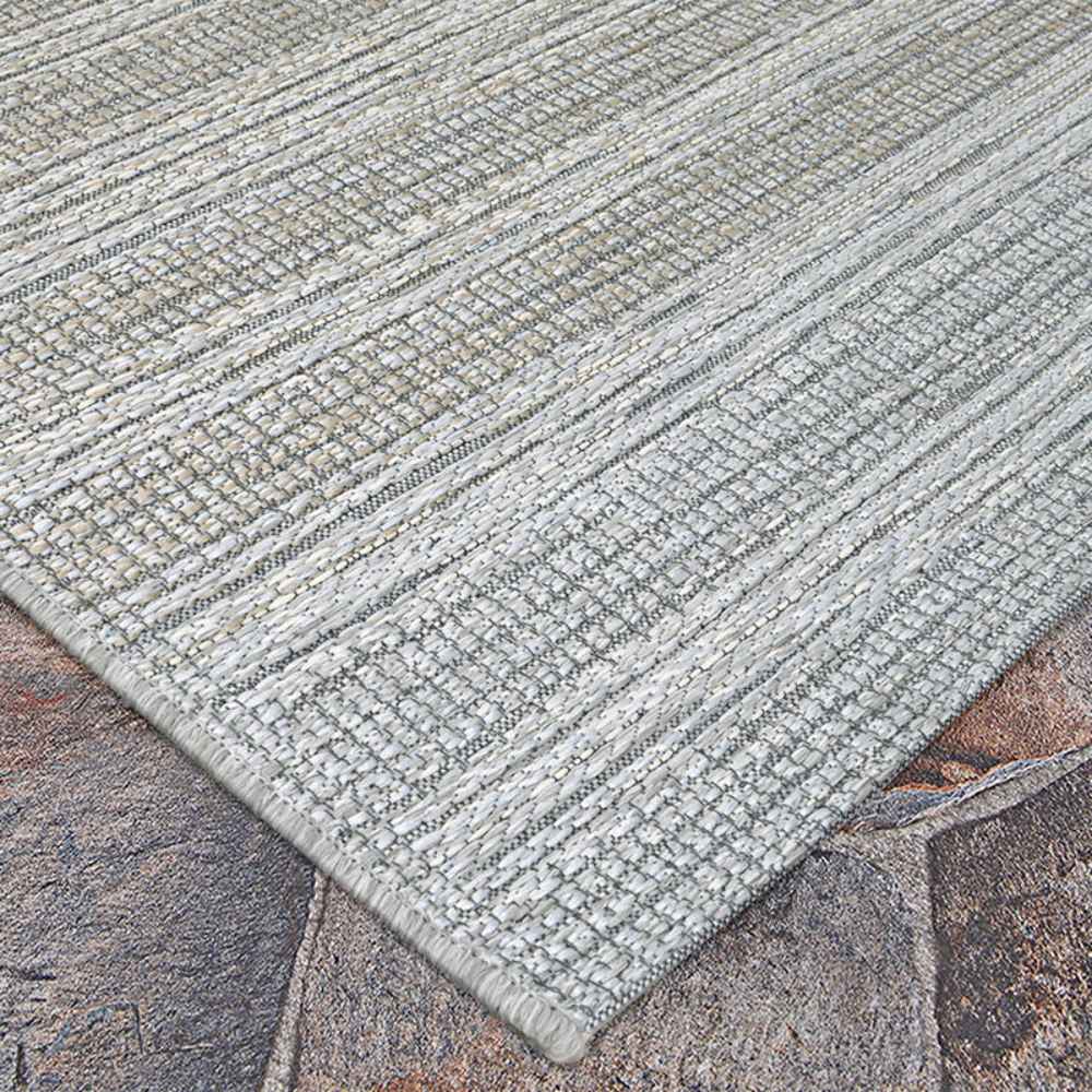 This image presents the Couristan Cape Indoor/Outdoor Rug - Shallows/Taupe-Grey laid flat on outdoor tile