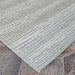 This image presents the Couristan Cape Indoor/Outdoor Rug - Shallows/Taupe-Grey laid flat on outdoor tile