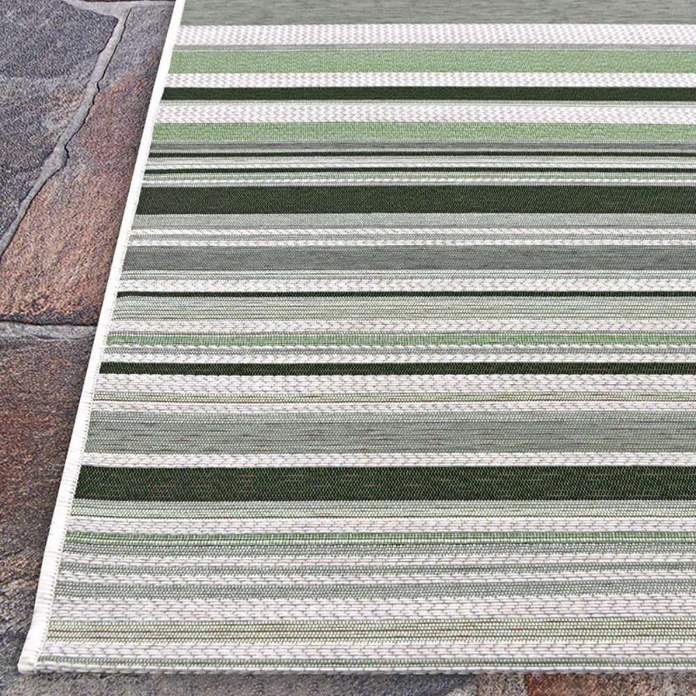 Top corner of Couristan Dolce Indoor/Outdoor Rug - Striped/Grass is displayed neatly against a stone surface