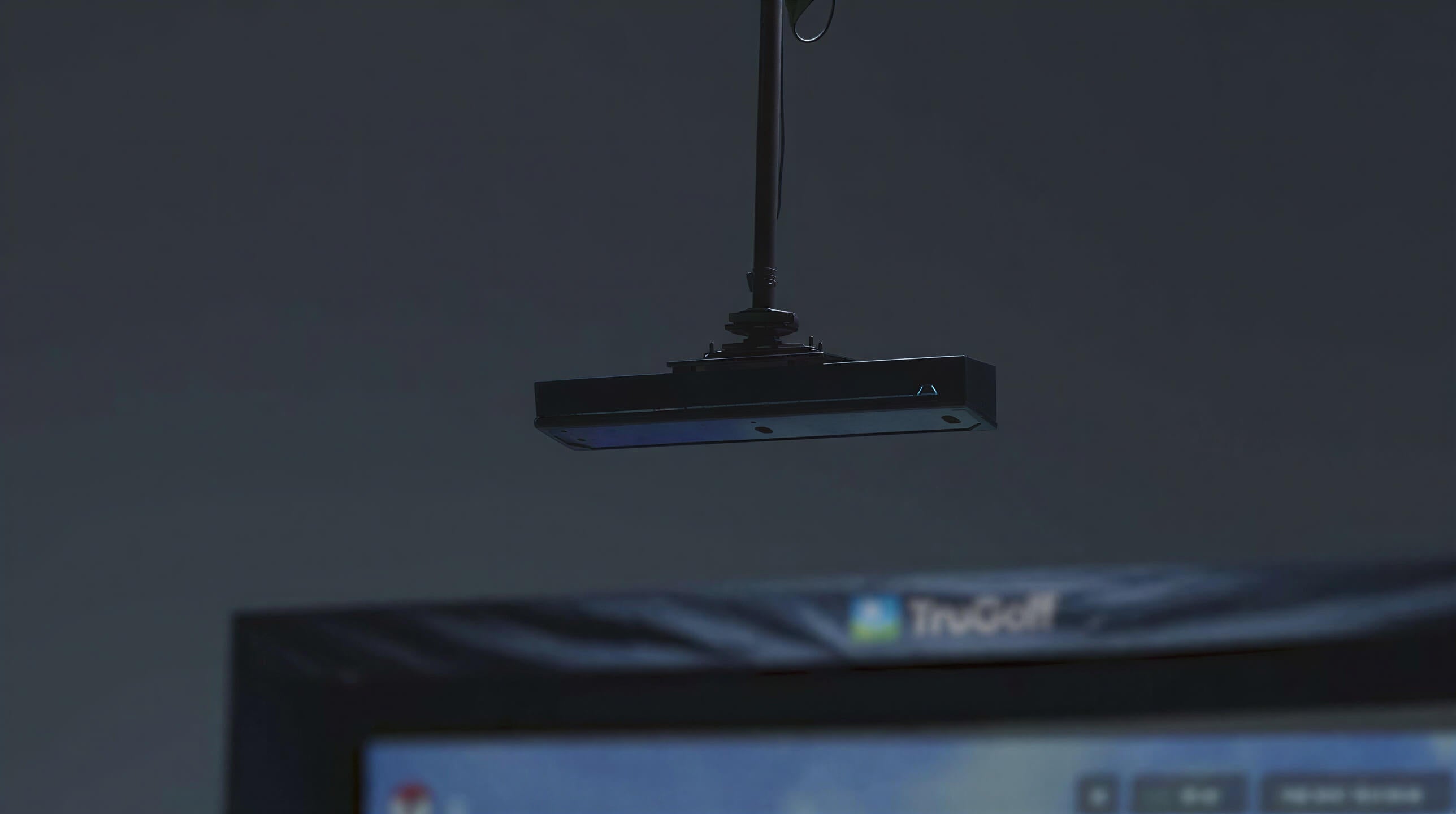 TruGolf APOGEE Golf Launch Monitor w/ MAX 4K Simulator is shown mounted on the ceiling above a golf simulator screen to track shots from above