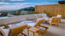Two Westminster Teak Horizon Chaise Lounger chairs with white cushions rest on a scenic patio overlooking the ocean