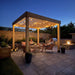 Two people relaxing under a lit pergola at night with the Outdoor Living Today Western Red Cedar Urban Escape Pergola