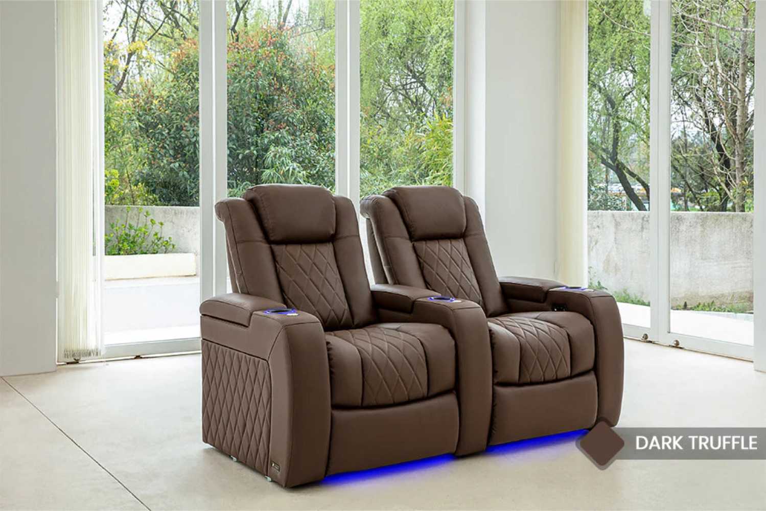 Two Valencia Tuscany Vegan Edition Home Theater Seating chairs in Dark Truffle finish, beautifully placed in a room with large windows overlooking lush greenery