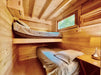 Two single beds, one lofted and one on the floor, fill a small wood-paneled room in the Sawmill Structures Edwin Lake House 70MM Garden Room