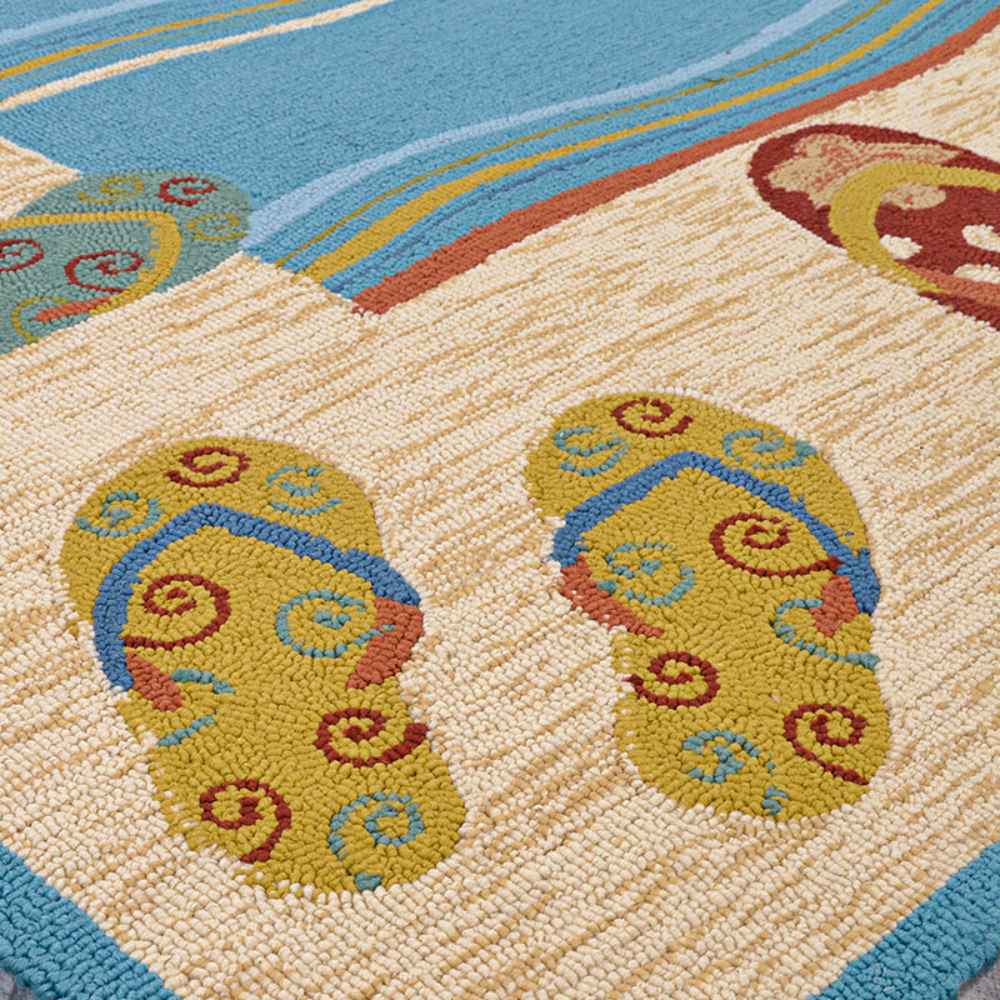 Two pairs of flip-flops in yellow and blue sit near a blue wave design on the Couristan Covington Indoor/Outdoor Rug - Sandals/Sand-Multi
