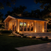 Illuminated wood Konrad 44 B cabin at night with glass doors, people inside, and outdoor lighting on a stone patio.