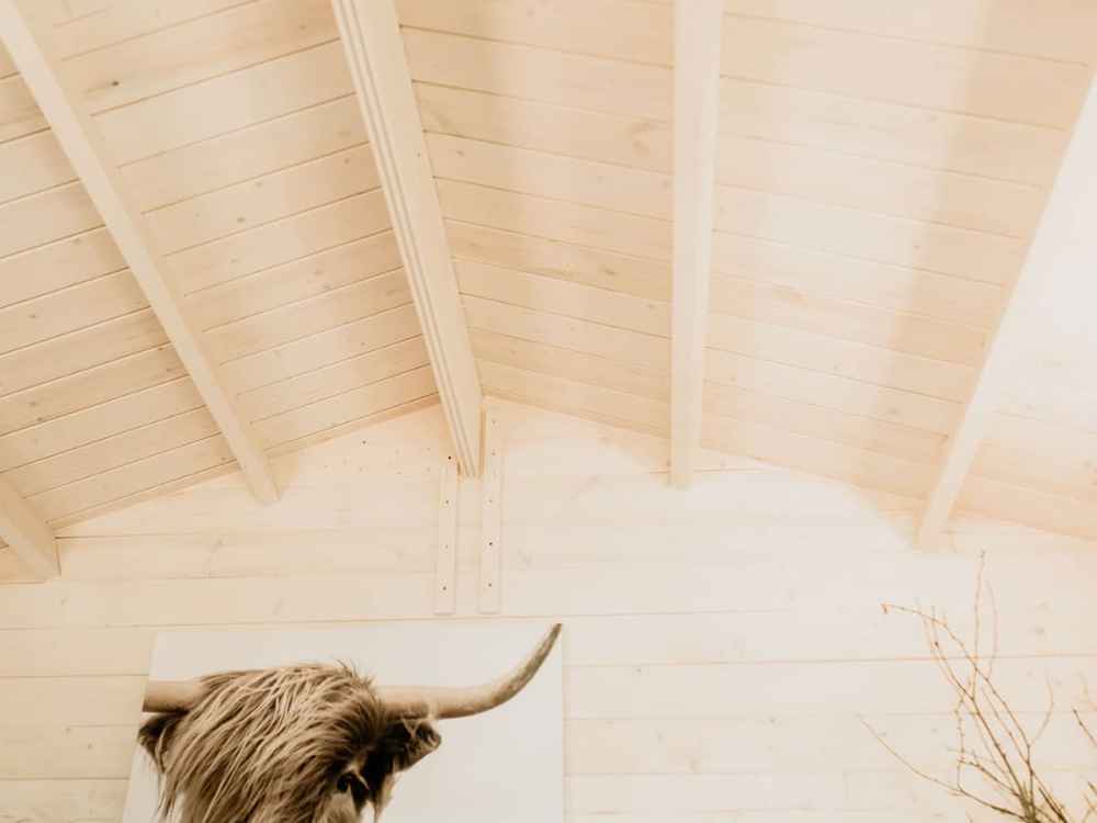 Upward view of a vaulted wooden ceiling with exposed beams in the Sawmill Structures Harvest Grand Bungalow 107 Garden Room