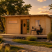 Urho 70 A wooden garden cabin at golden hour with a man working at a modern desk on the outdoor deck.
