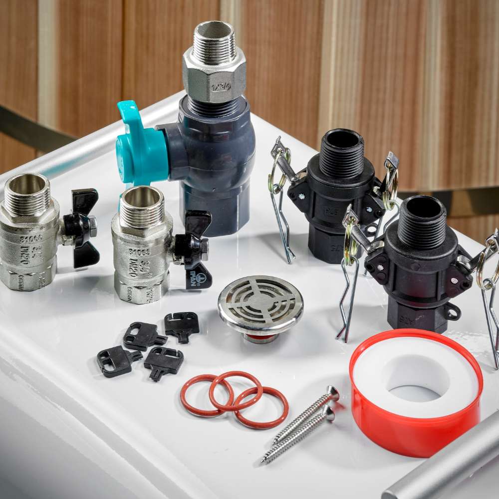 Valves, hose connectors, a drain grate, red O-rings and white thread seal tape for Golden Designs Dynamic Cold Therapy Cuboid Plastic Cold Plunge Tub are spread across a white surface