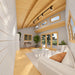 Sunlit Versa 160 Atrium 70MM interior with a white sofa, desk, potted tree, tall glass doors, clerestory windows, and exposed curved beams.