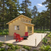 Angled forest view of the Versa 160 Atrium 70MM with a pale wood exterior, raised clerestory, glazed doors, red Adirondack chairs, and a deck fire bowl.