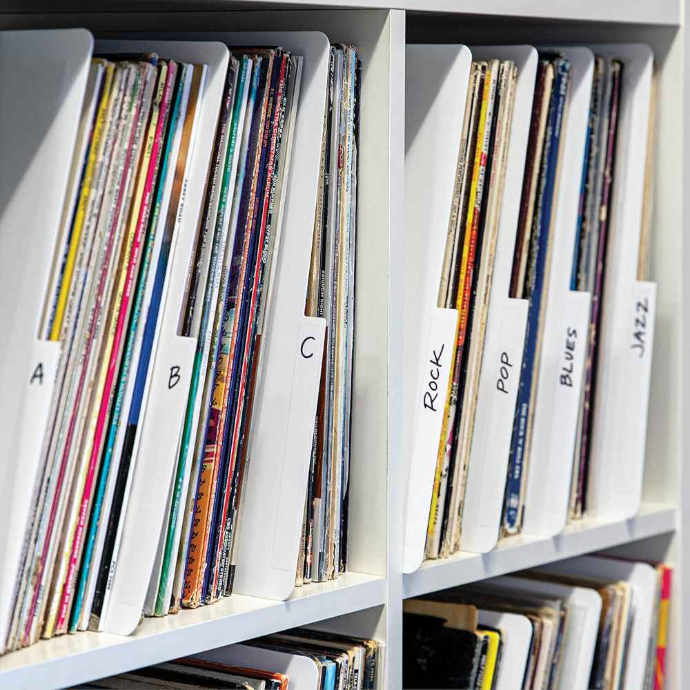 Vinyl records are neatly organized on shelves, categorized using labeled Crosley Vinyl Record Dividers - White