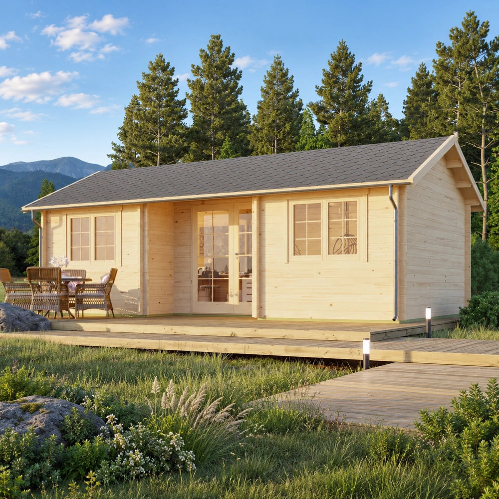 Wallis 44 wooden garden room with a dark gabled roof, glazed door and paired windows, set on a wooden deck with outdoor dining furniture amid trees and mountain scenery.