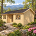 Wallis 44 Freedom Office in a sunny western North Carolina landscape, shown from the front-right angle with Blue Ridge Mountains, rhododendrons, native trees and a professional home office visible through the windows.