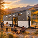 Wanderlove House on Wheels beside a Colorado alpine lake at golden hour, with four adults preparing dinner, sharing drinks, and relaxing around a small campfire.
