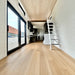 Bright Wanderlove Tiny Home hallway with light wood flooring, white shiplap walls, large black-trimmed windows, and stairs leading to the loft.