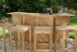 Westminster Teak 5pc Somerset Teak Bar & Stool Set outdoor setup with four stools and a bar topped with wine glasses and a bottle, set against lush tropical plants