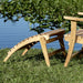 Westminster Teak Adirondack Footrest placed outdoors beside an Adirondack chair near water, showing a relaxing outdoor setup