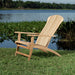 Westminster Teak Adirondack Lounger in natural teak sits on grass beside a calm lake, showing its curved reclining back and wide armrests