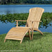 Westminster Teak Adirondack Lounger on grass with a matching wooden footrest, creating a relaxing outdoor seating setup